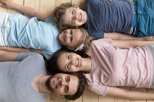 Familie liegt Kopf-an-Kopf auf Boden